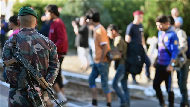 Migrantes que suben a un tren bajo la mirada vigilante de un soldado húngaro en la región de Magyarboly.   