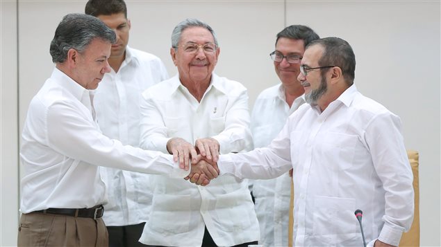 El presidente cubano Raul Castro entre el presidente colombiano Juan Manuel Santos (izq) y el líder de las FARC Rodrigo Londoño (der) 