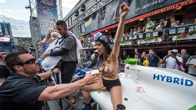La photographie montre deux militantes du groupe Femen, le torse nu, lors des festivités du Grand Prix du Canada.