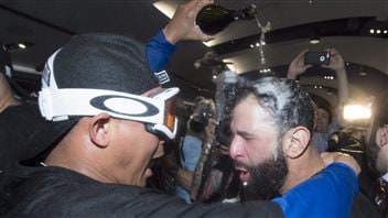 Utility player Ezequiel Carrera, left, douses slugger Jose Bautista with champagne after the Jays eliminated the Texas Rangers Wednesday night. Carrera, wearing celebration goggles, shouting with joy as he wraps his right arm around Bautista's shoulder and empties a bottle over Bautista's head with his left hand. The black bearded Bautista's hair is drenched and and his expression is one of woooofffff.