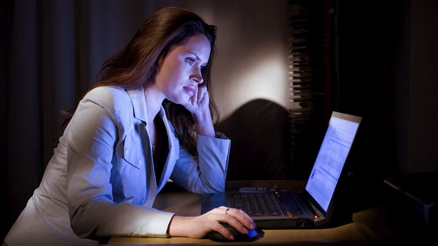 femme devant ordinateur dans une pièce sombre