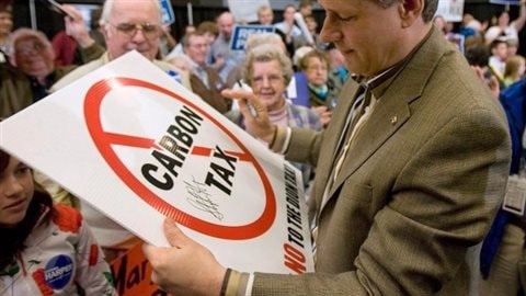 Le premier ministre sortant Stephen Harper avec entre les mains une enseigne contre la taxe au carbone lors d’un rassemblement de partisans conservateurs l’an dernier.