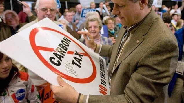 Stephen Harper avec entre les mains une enseigne contre la taxe au carbone lors d’un rassemblement de partisans conservateurs l’an dernier.