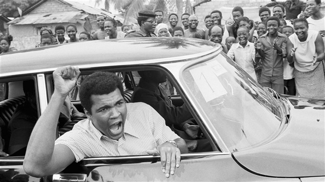 Mohamed Ali s'adresse à ses partisans pendant un tour de ville en voiture de Kinshasa, un mois et demi avant son combat contre George Foreman. Mohamed Ali s'adresse à ses partisans pendant un tour de ville en voiture de Kinshasa, un mois et demi avant son combat contre George Foreman.