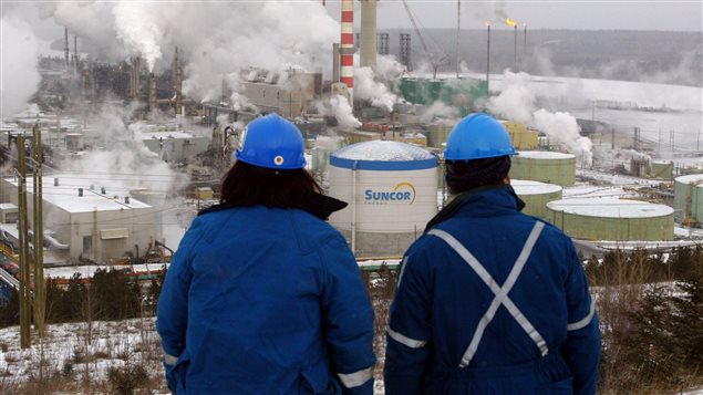 Des ouvriers observent au loin l’usine de pétrole de Suncor en Alberta