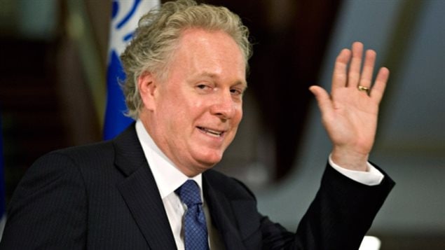 Jean Charest (seen in 2014) says he not interested in running for the Conservative Party's leadership. We see Charest's right profile from mid-chest up. He is dressed in a sharp, dark pin-striped suit and fancy tie and he is waving with his left hand. Under his still curly blondish hair, he wears a very strange expression, one marked with just of touch of fear and foreboding, as if preparing to meet someone whose name he can't quite remember.