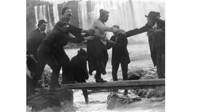 The shaken, slightly dazed, but alive and unharmed 63-year-old Annie Taylor being helped to shore after a rowboat pulled the barrel to the Candian side below the Falls.