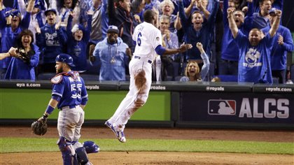 Cain raises to suit the occasion. We see Cain to the right of the photo leaping into the air as the fans continue to go nuts in the stands. Martin is looking out at the infield ready to make a play.