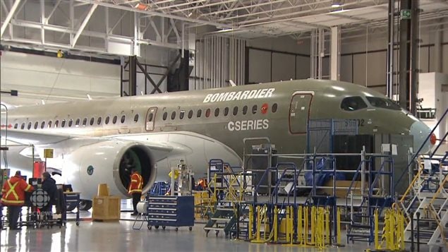 CSeries assembly plant in Mirabel, Quebec. The image shows workers at the Bombardier CSeries assembly plant working on a grey plane.