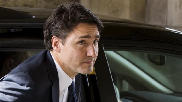 In coming Prime Minister Justin Trudeau has proposed to the top marginal income tax rate on those earning $205,000 or more. We see Trudeau from just below the neck exiting the back seat of a government car. He wears a dark, blue suit and dark tie and is looking forward toward his destination, the funeral on Tuesday in Toronto for former Canadian ambassador Ken Taylor.
