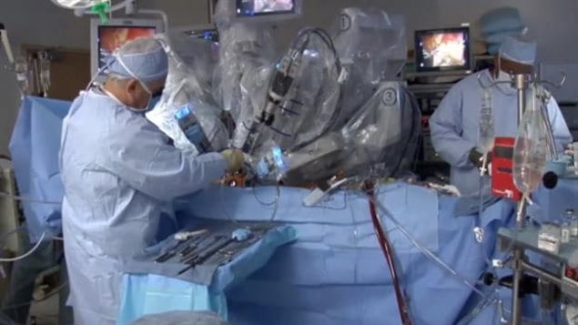New studies have found that following a kidney transplant surgery (above), some treatments have been--to understate it--less than optimal. We see an operating room in which the dominant colour is blue. The surgeons are all in blue so is the sheet covering the patient. We see two surgeons in caps and masks. The lead surgeon is stationed at the left and appears to be cutting into the patient's stomach. The other surgeon is to the right behind what appears to be a red monitoring device. Above the patient are a series of surgical tools under transparent covering.