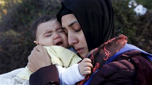 A Syrian refugee hugs her crying baby after arriving on a raft on the Greek island of Lesbos, October 27, 2015. According to United Nations over half a million refugees and migrants have arrived by sea in Greece this year and the rate of arrivals is rising, in a rush to beat the onset of freezing winter.
