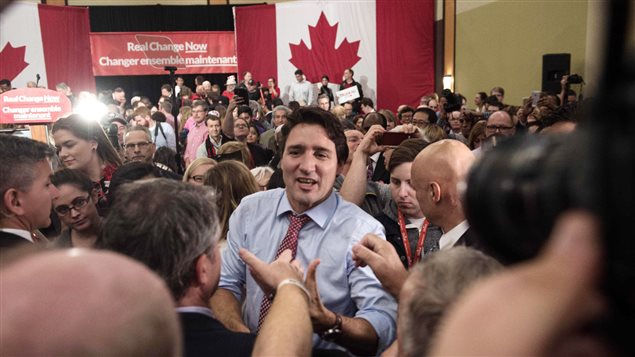 anadian Liberal Party leader Justin Trudeau in a crowd at a victory rally in Ottawa on October 20, 2015 after winning the general elections. Canadian flags are hung in the background of a room filled with Liberal supporters.