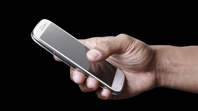 Un homme tient un téléphone intelligent. Un homme tient un téléphone intelligent.
