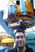 George Conidis in front of the 2.1m telescope which he used to collect data which was paramount to his discovery of why galaxies spin.