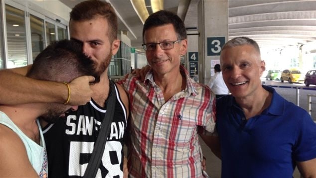 Aamer, dont le visage est caché parce qu'il n'a pas révélé son identité sexuelle à sa famille, et son partenaire Danny Ramadan arrivent à l'aéroport international de Vancouver en 2014, grâce à l'aide de deux Canadiens, David Salter et Ron Rosell, à droite. (Margaret Gallagher)