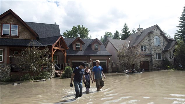 Calgary residents walk through flood waters on June 24, 2013. The Home Adaptation Audit, created by the Intact Centre for Climate Adaptation, will help Canadians protect their homes from flooding.