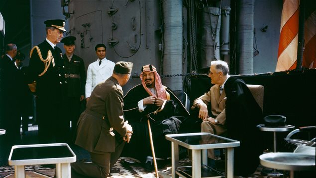 الرئيس الأميركي فرانكلين روزفلت (إلى اليمين) وإلى يمينه مؤسس المملكة العربية السعودية الملك عبدالعزيز آل سعود الذي يتحدث إلى المترجم، الكولونيل وليام إيدي، على متن المدمرة "كوينسي" في البحيرة المرة الكبرى في قناة السويس في 14 شباط (فبراير) 1945.