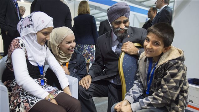 Canada’s Minister of National Defence Harjit Sajjan speaks with members of a Syrian family at a refugee processing centre in Amman, Jordan on Nov. 29, 2015.
