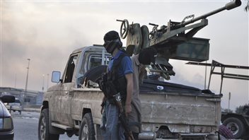 ISIS fighters stand guard at a checkpoint in the Iraqi city of Mosul on June 11, 2014.