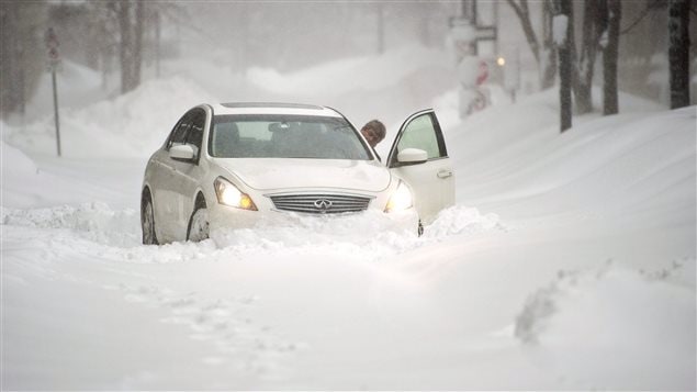 Un automobiliste voit son véhicule immobilisé à cause de la neige.