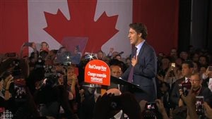 Justin Trudeau won a healthy majority in Canada's Oct. 19 federal election. We see Trudeau standing behind a podium surrounded by admirers with a giant Canadian flag in the background.