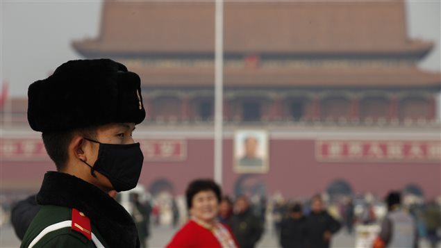 Un policía chino en la plaza de Tiananmen con una máscara para protegerse de la contaminación ambiental.