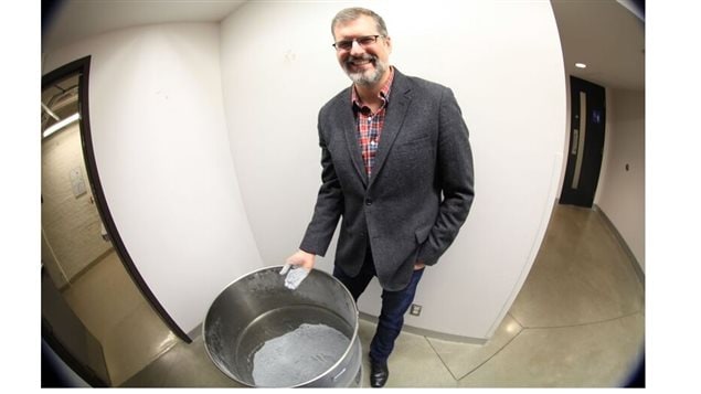 Professor Jeffrey Bergthorson with his hand covered after dipping it in the barrel filled with finely ground aluminium powder fuel.