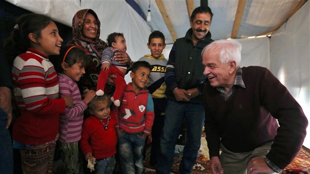  Canadian Minister of Immigration John McCallum, right, speaks with a Syrian family inside their tent, during his visit to a refugee camp in the southern town of Ghaziyeh, near the port city of Sidon, Lebanon, Friday, Dec. 18, 2015. 