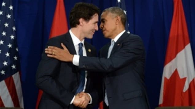 Justin Trudeau, left, and Barack Obama met briefly at the APEC Summit in Manila in November. We see Obama patting Trudeau's right shoulder with his right hand. Their faces are inches apart as the American flag stands behind them on the left and the Canadian flag on the right.