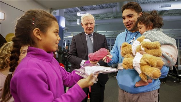  The Governor General of Canada David Johnston greets Syrian refugees as his granddaughter Tea gives a man and his daughter a toque at the Pearson Toronto International Airport in Mississauga, Ontario, December 18, 2015.