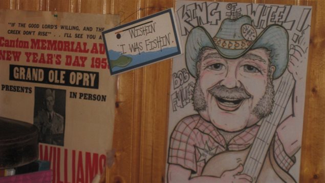 *King of the Wheel* caricature of Bob Fuller with his iconic blue cowboy hat on the wall of the stage alongside an original poster of Hank williams at the Grand Ol Opry
