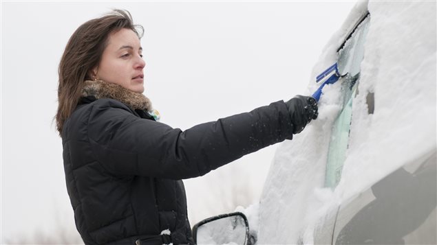 Une femme déneige sa voiture. Une femme déneige sa voiture.