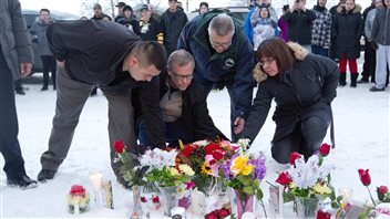 La Loche Mayor Kevin Janvier, left to right, Saskatchewan Premier Brad Wall, federal Public Safety Minister Ralph Goodale and MLA Georgina Jolibois lay flowers at a makeshift memorial at La Loche, Sask., on Sunday. January 24, 2016. A shooting Friday left four people dead.