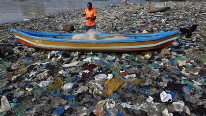 A fisher is surrounded by discarded plastic bags on the shores of the Arabian Sea in Mumbai, India.