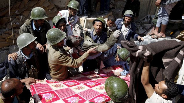  Policemen carry the body of a dead fellow policeman, that they recover from the site of a Saudi-led air strike on the police headquarters in Yemen’s capital Sanaa, January 18, 2016.