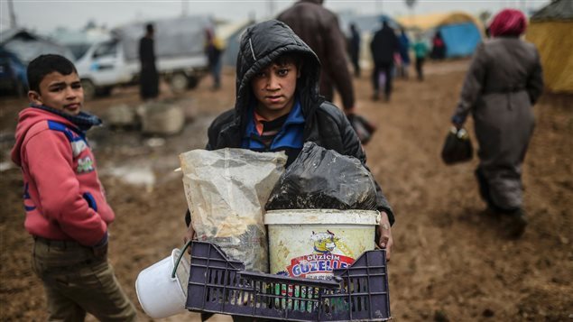 Niños sirio transporta algunos efectos personales en el campo de Bab Al-Salama, cerca de Azaz, a proximidad de la frontera turca.