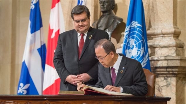 United Nations Secretary General Ban Ki-moon, right, signs the guest book as Montreal mayor Denis Coderre looks on at Montreal City Hall on Friday. (Paul Chiasson/Canadian Press)