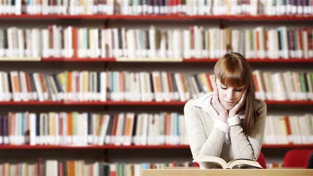 Femme lisant un livre dans une bibliothèque.