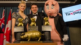 A presenter (left) and Aaron Wudrick (centre) with the CTF mascot and pigs at the public trough trophies.