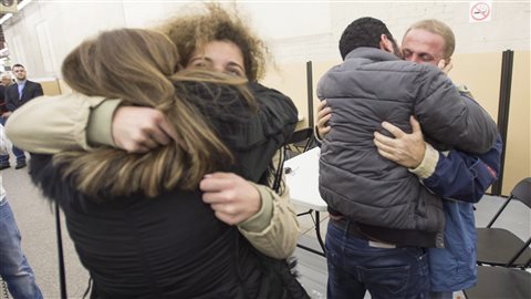 Des réfugiés partis d’Alep en Syrie sont accueillis à leur arrivée à Montréal par des membres de leur famille, en décembre 2015.