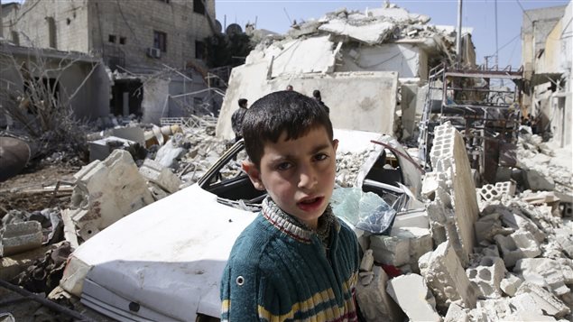Un niño frente a las ruinas en Siria