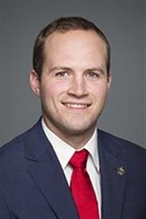 Liberal MP Nathaniel Erskine-Smith. We see him in a dark suit and red tied looking directly at the camera with his mouse just a touch agape. His blond hair is beginning to thin just a tad.