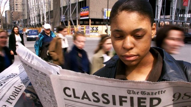 Une femme cherche du travail dans les pages du quotidien anglais The Gazette de Montréal. Photo crédit CBC