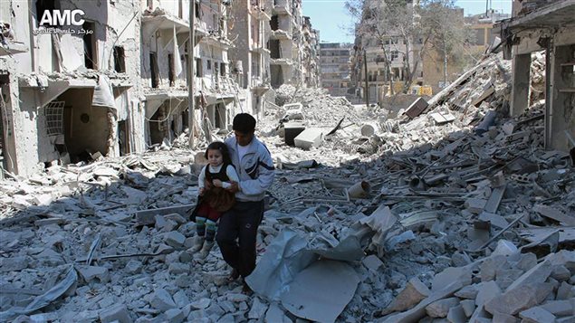  In This April 21, 2014, file photo shows a Syrian man holding a girl as he stands on the rubble of houses that were destroyed by Syrian government forces air strikes in Aleppo, Syria.