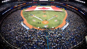 Stadiums across the MLB spectrum are filled for Opening Days. Rogers Centre is no exception. Here's the crowd in 2014. We have an overhead photo from the top deck behind homeplate We see a packed house with the players lined up on the baselines following their introductions. In centre field a giant Canadian flag has been unfurled. It stretches from foul line to foul line.