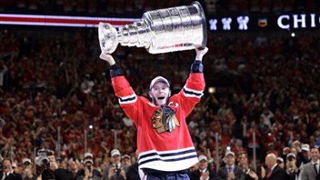 Chicago defeated the Tampa Bay to win the 2015 Stanley Cup. At least the man hoisting the Cup is Canadian--Jonathan Toews of Winnipeg. We see Toews from the knees up. He wears the red hawks jersey with its famous logo and the letter C on his left shoulder. Toews has a look of ecstasy as he hoists the cup over his head.