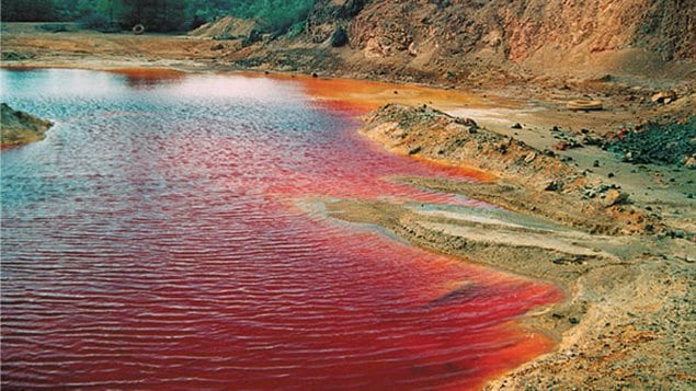 The first oxygen-dependent life on land may have been bacteria that *eat* pyrite, also known as fool’s gold. Similar bacteria still exist at mining waste sites, where pyrite has been discarded creating highly acidic conditions. Above, a modern-day acidic drainage at an abandoned copper mine. Analyzing copper isotopes, Konhauser and an international team have help date when oxidation of Earth’s atmosphere occured