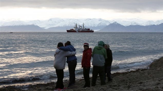 Local children stand on the shore as the Coast Guard ship Des Groseilliers sits in the waters near the Arctic community of Pond Inlet, Nunavut August 23, 2014. Chris Wattie/REUTERS