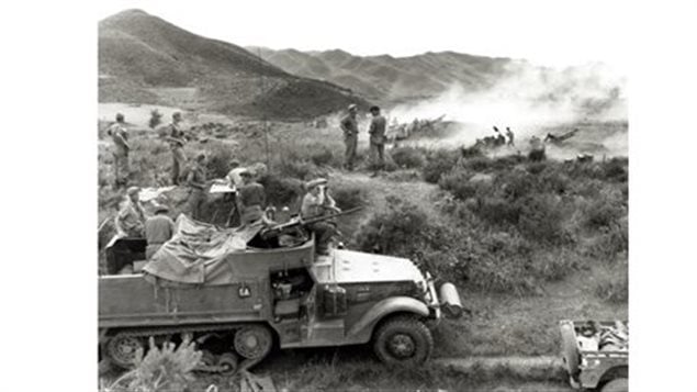 M3 haltrack with 50 cal. as smoke rising from the dug-in 25pdr guns of the 2nd Battalion, Royal Canadian Horse Artillery give supporting fire to troops of 2nd Battalion, Royal Canadian Regiment, during the Korean War, June 1951. The hilly and difficult nature of terrain seen in background